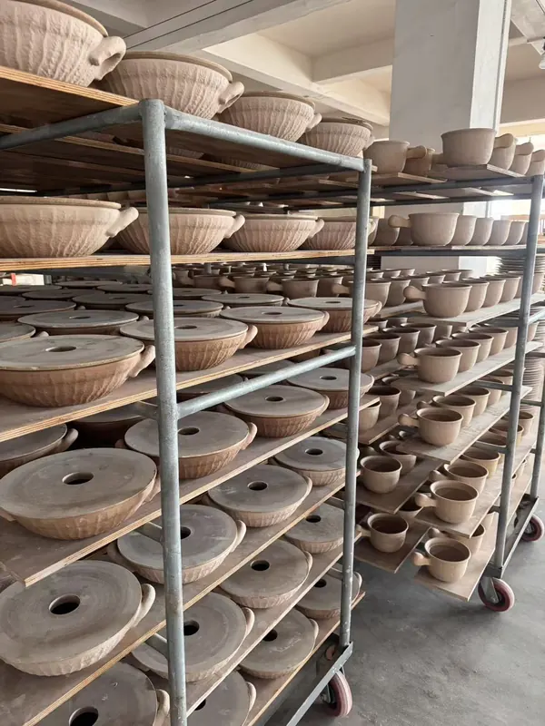 Pots and lids drying on racks before firing.